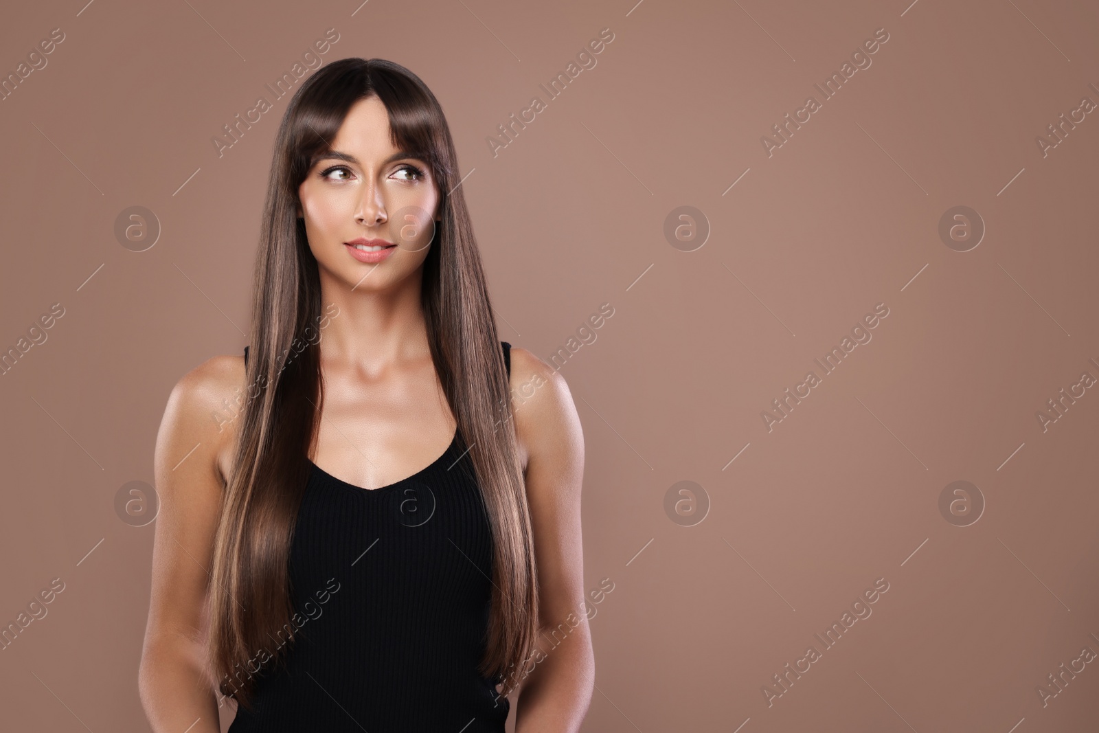 Image of Attractive woman with shiny straight hair on brown background, space for text. Professional hairstyling