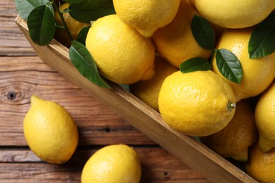 Fresh lemons in crate on wooden table, top view