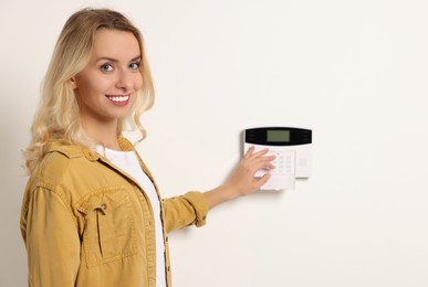 Photo of Smiling woman entering code on home security system indoors