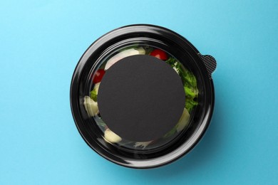 Tasty food in container on light blue background, top view. Space for text