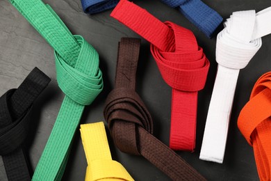 Photo of Colorful karate belts on gray background, flat lay