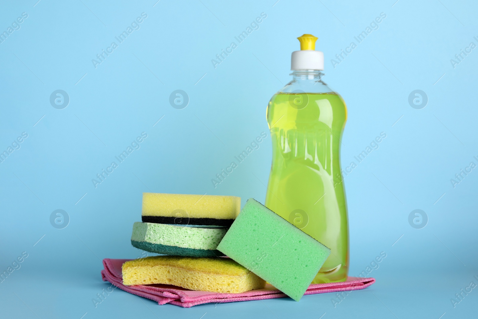 Photo of Sponges and other cleaning products on light blue background