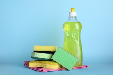 Sponges and other cleaning products on light blue background