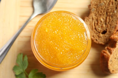 Photo of Fresh pike caviar in glass jar, bread and parsley on wooden board, top view