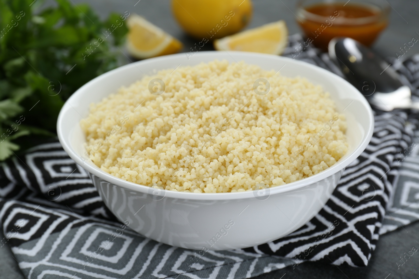 Photo of Bowl of tasty couscous on grey table, closeup