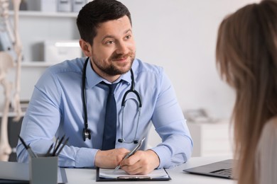 Photo of Professional doctor working with patient at white table in hospital