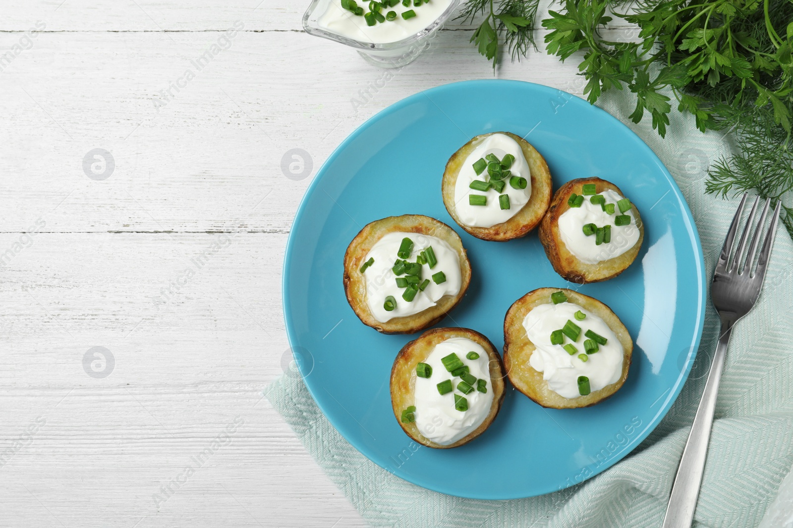 Photo of Delicious potato wedges with sour cream served on white wooden table, flat lay. Space for text