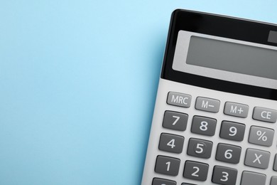 Calculator on light blue background, top view. Space for text