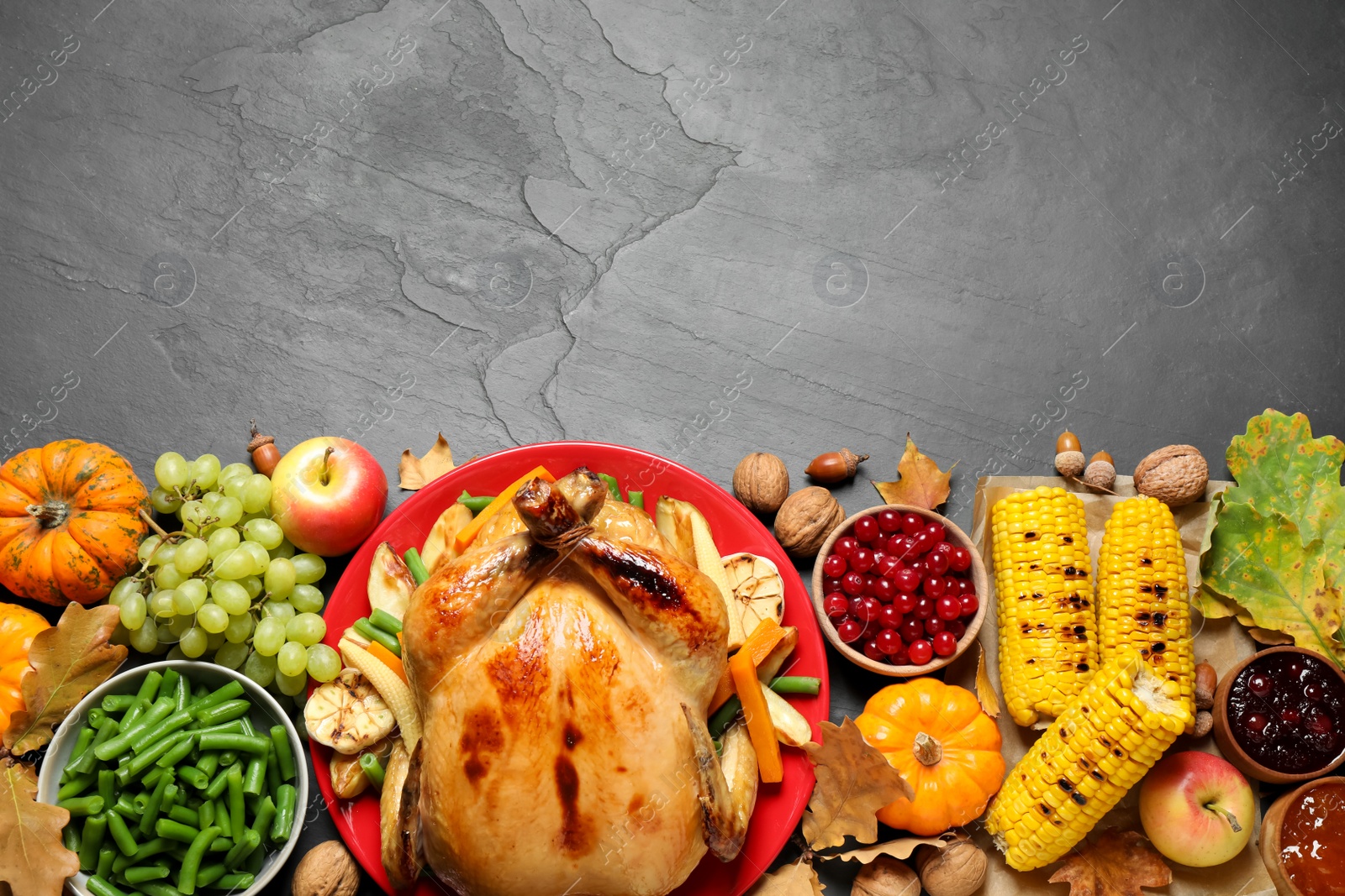 Photo of Traditional Thanksgiving day feast with delicious cooked turkey and other seasonal dishes served on black table, flat lay. Space for text