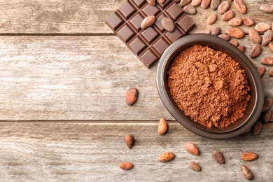 Photo of Flat lay composition with cocoa powder, beans and chocolate bar on wooden background