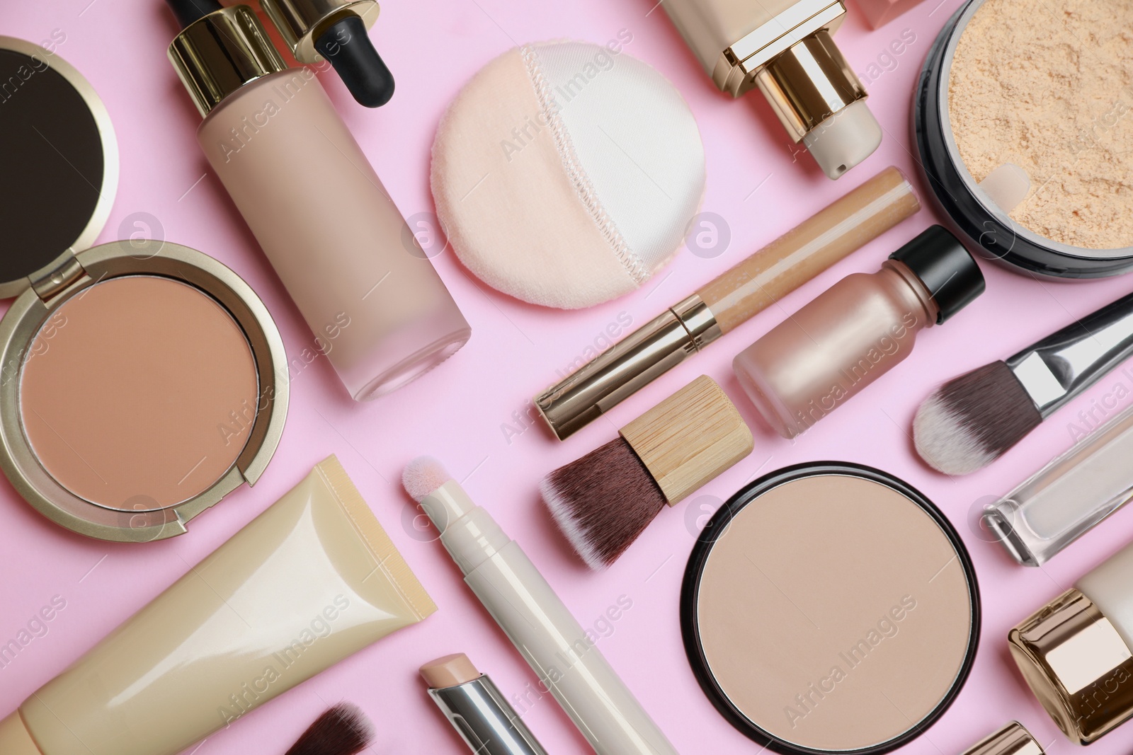 Photo of Face powders and other decorative cosmetic products on pink background, flat lay