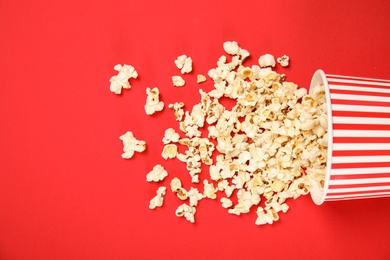 Paper cup with tasty fresh popcorn on color background, top view