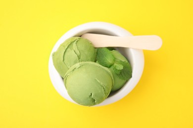 Photo of Tasty matcha ice cream in bowl on yellow background, top view