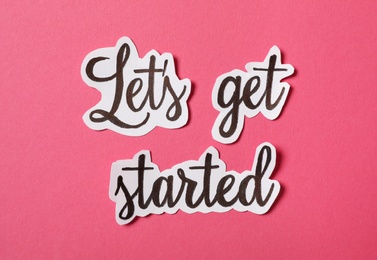 Photo of Sheets of paper with phrase Let's Get Started on pink background, flat lay