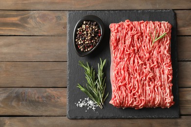 Photo of Raw ground meat, spices and rosemary on wooden table, top view. Space for text