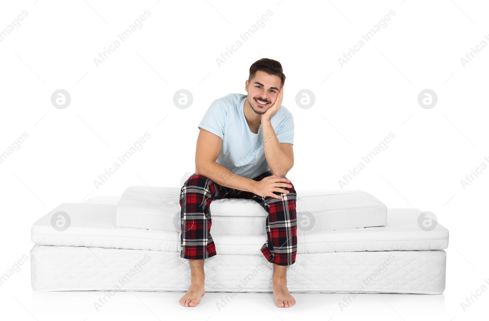 Photo of Young man sitting on mattress pile against white background