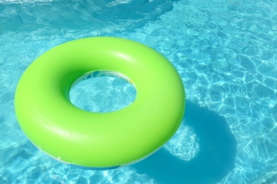 Bright inflatable ring floating in swimming pool on sunny day. Space for text