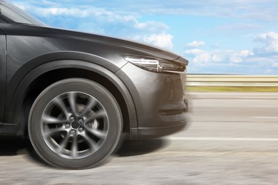 Black car driving on road outdoors, motion blur effect. Space for text