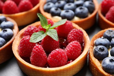 Photo of Tartlet with fresh raspberries on table, closeup. Delicious dessert