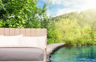 Image of Comfortable bed with soft pillows and beautiful view of river and mountain on background