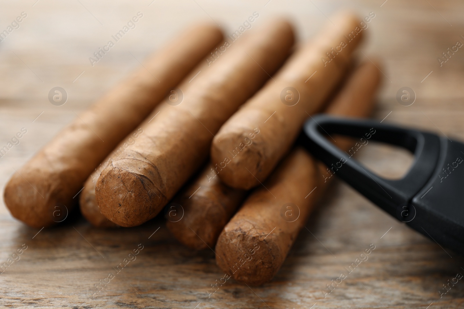 Photo of Cigars wrapped in tobacco leaves on wooden table, closeup