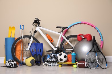 Bicycle and different modern sport equipment near beige wall