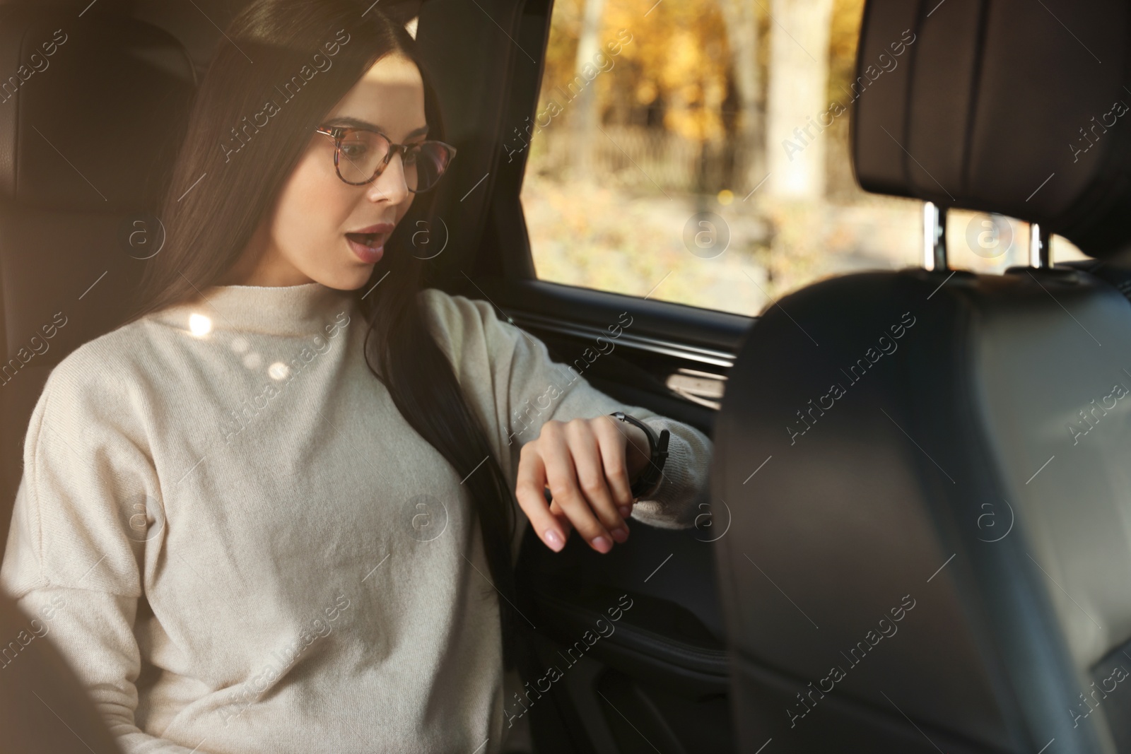 Photo of Emotional woman checking time on watch in car. Being late concept