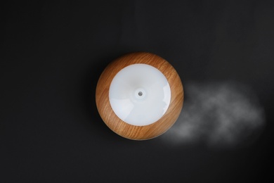 Photo of Modern essential oil diffuser on black background, top view