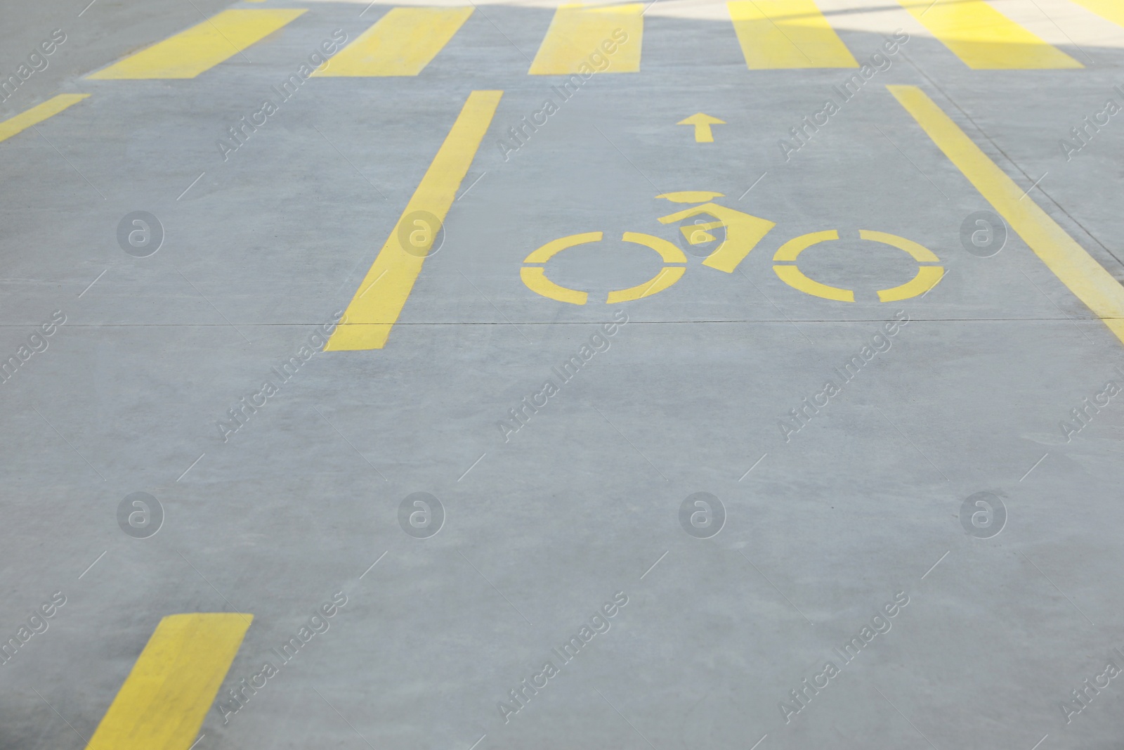 Photo of Bike lane with painted yellow bicycle sign and arrow near pedestrian crossing