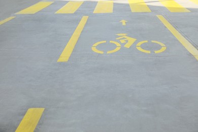 Photo of Bike lane with painted yellow bicycle sign and arrow near pedestrian crossing