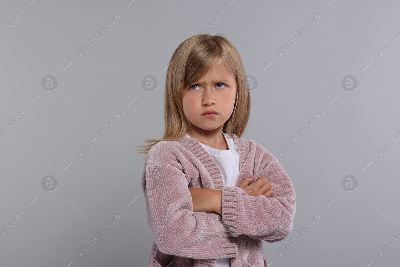 Photo of Resentful girl with crossed arms on grey background