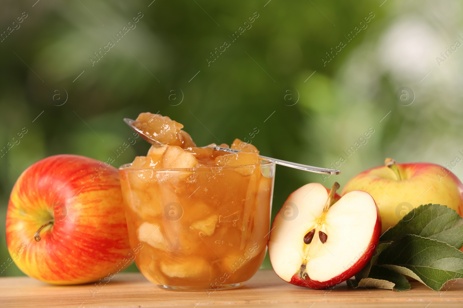 Photo of Delicious apple jam and fresh fruits on wooden table