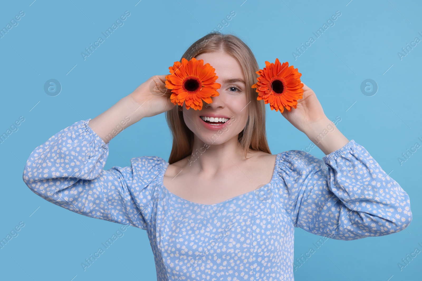 Photo of Beautiful woman with spring flowers in hands on light blue background