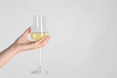 Photo of Woman holding glass of white wine on light background, closeup. Space for text