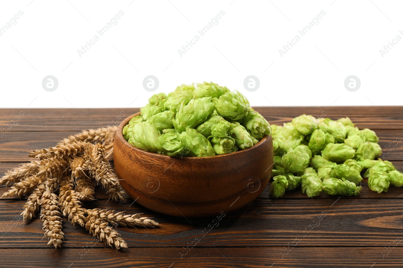 Photo of Fresh hop flowers and wheat ears on wooden table against white background