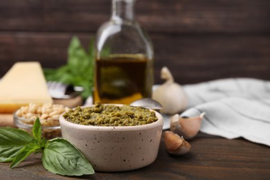 Photo of Tasty pesto sauce and ingredients on wooden table, closeup. Space for text