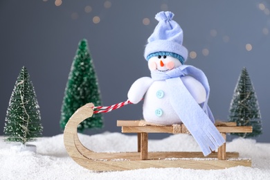 Photo of Sleigh with toy snowman on pile of snow