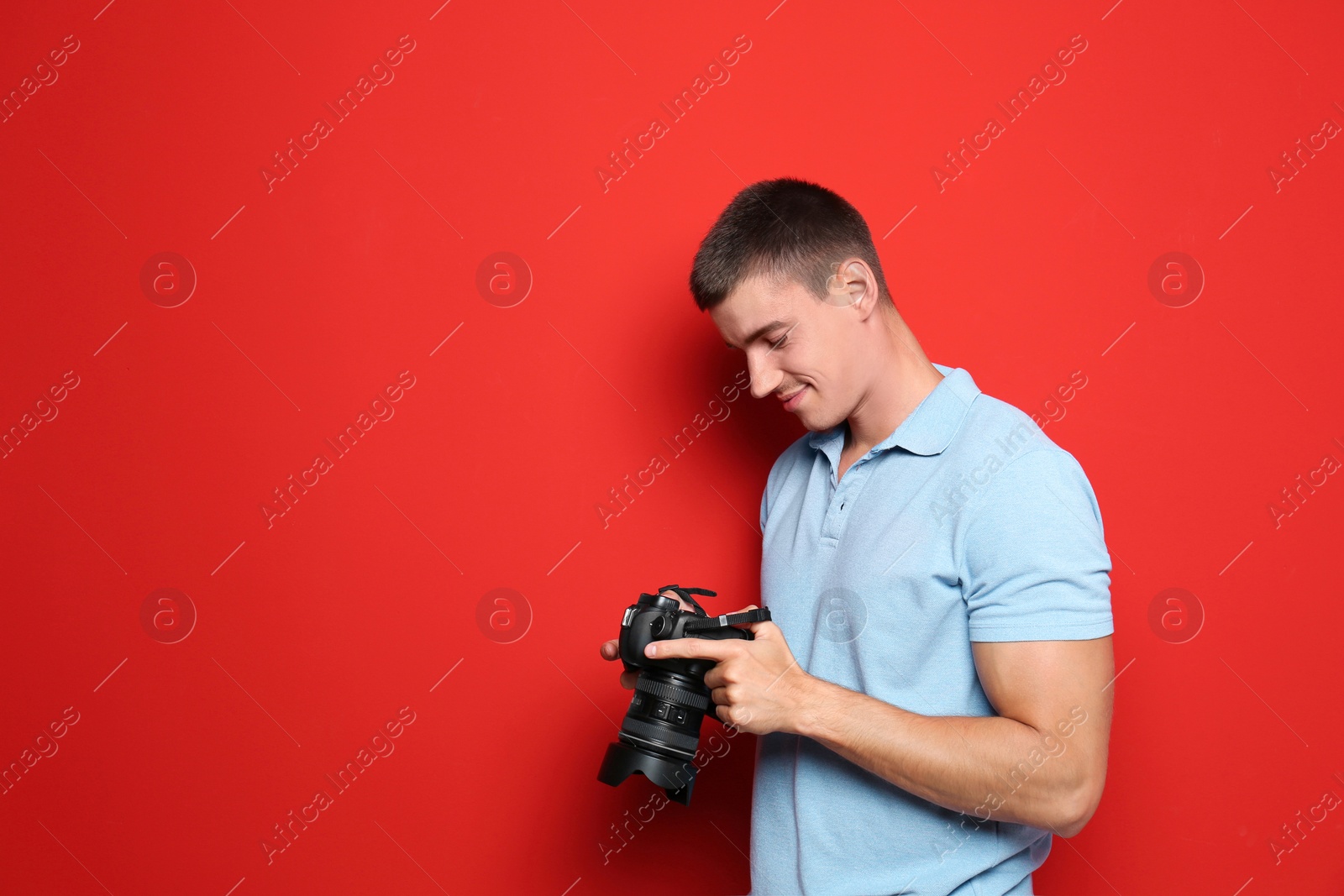 Photo of Young photographer with professional camera on red background. Space for text