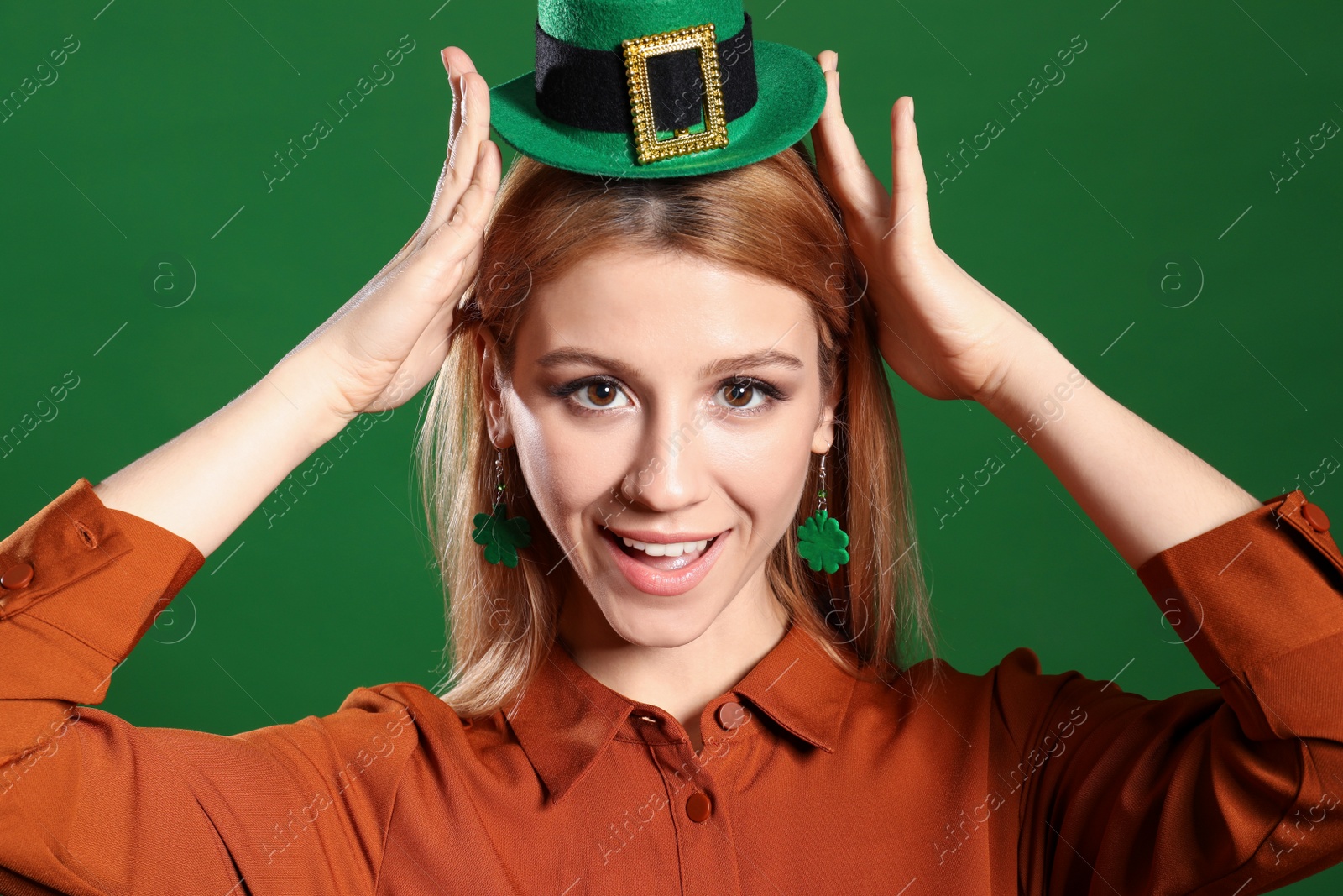 Photo of Young woman in leprechaun hat on green background. St. Patrick's Day celebration