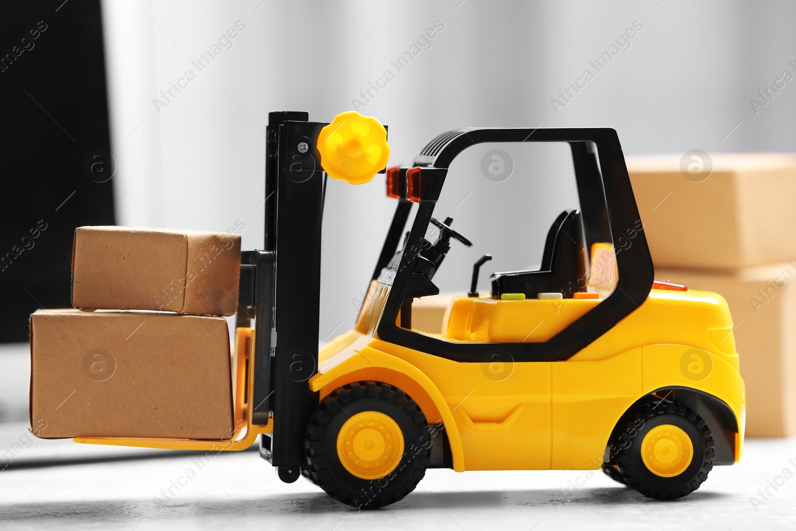 Photo of Toy forklift with boxes near laptop on table. Logistics and wholesale concept