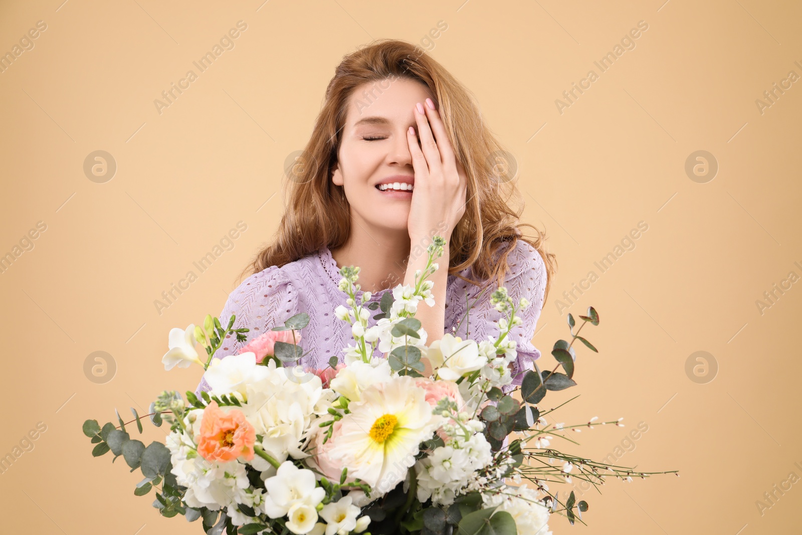 Photo of Beautiful woman with bouquet of flowers on beige background