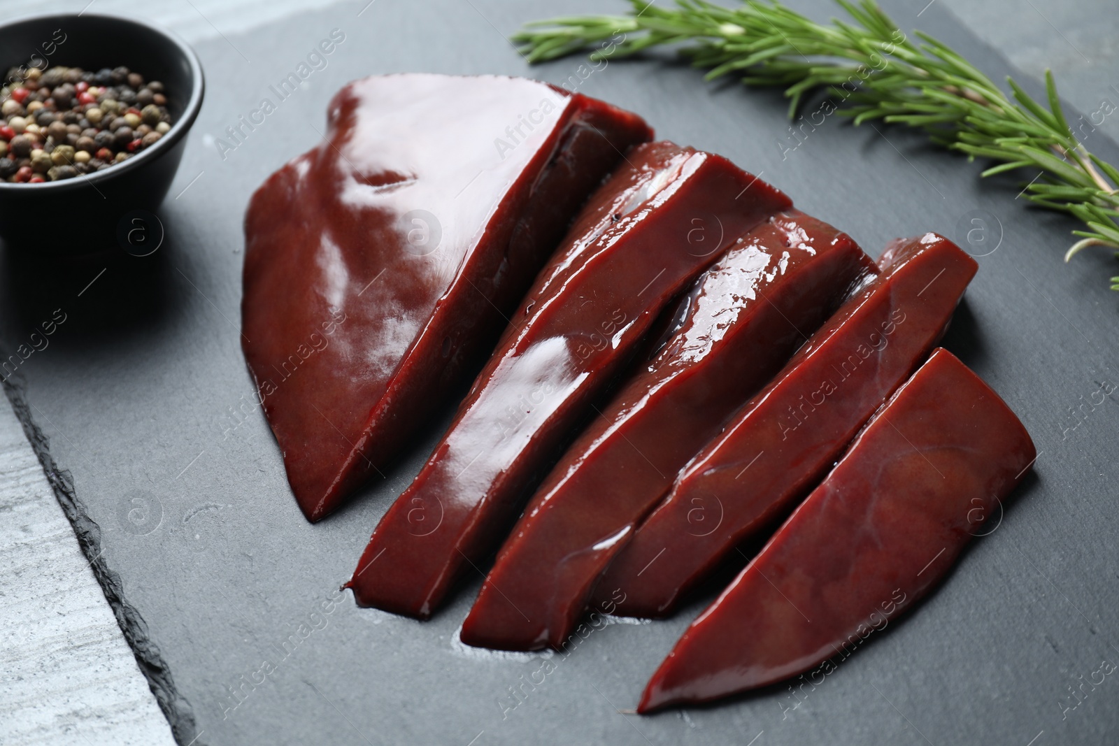 Photo of Cut raw beef liver on black table, closeup