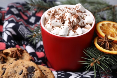 Photo of Cup of tasty cocoa with marshmallows on knitted cloth, closeup