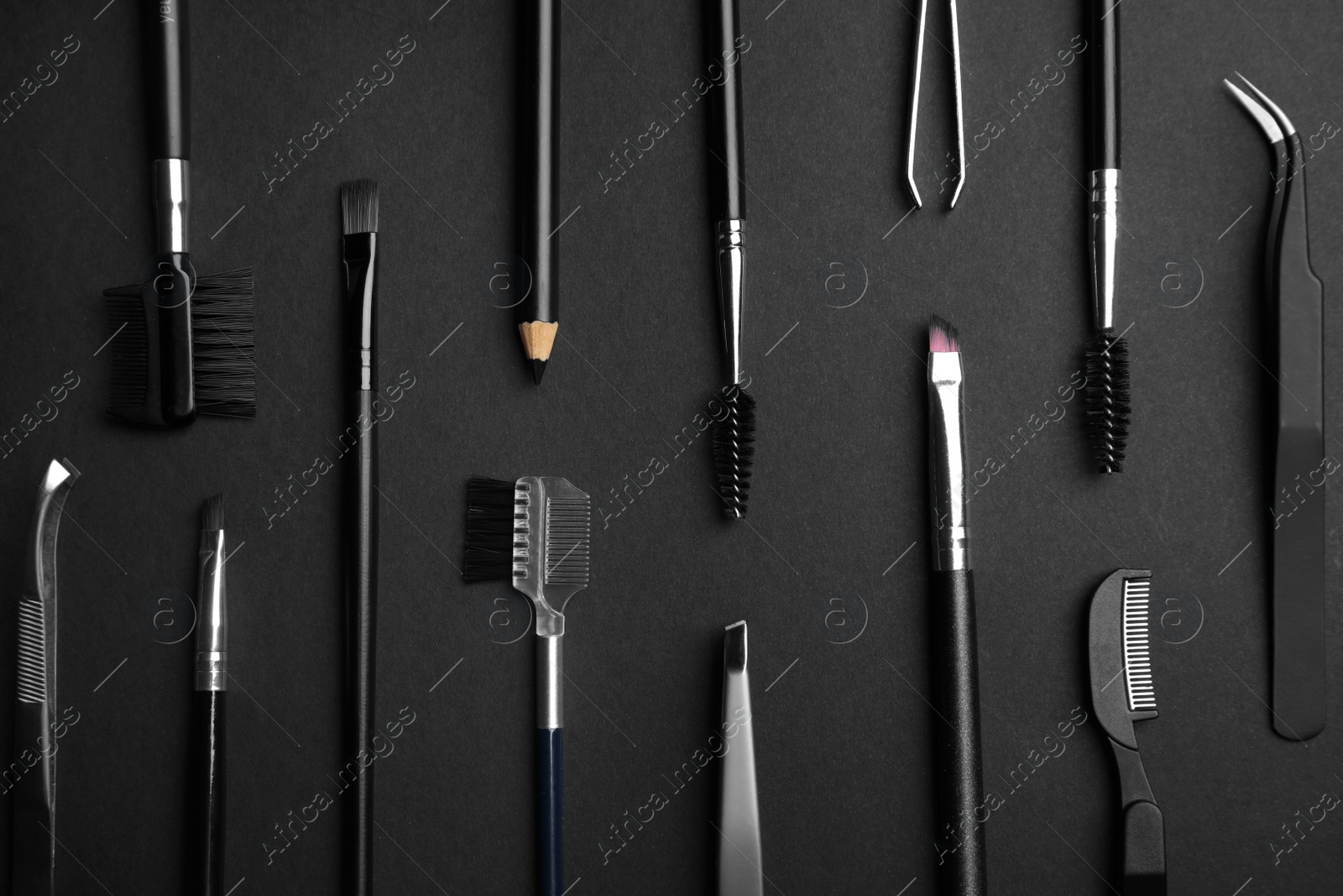 Photo of Set of professional eyebrow tools on black background, flat lay