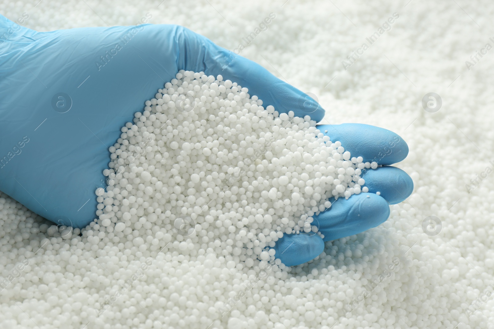 Photo of Person in gloves taking pellets of ammonium nitrate from pile, closeup. Mineral fertilizer