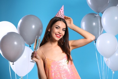 Photo of Portrait of happy woman with champagne in glass and party balloons on color background