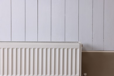 Photo of Modern radiator on white wooden wall. Central heating system