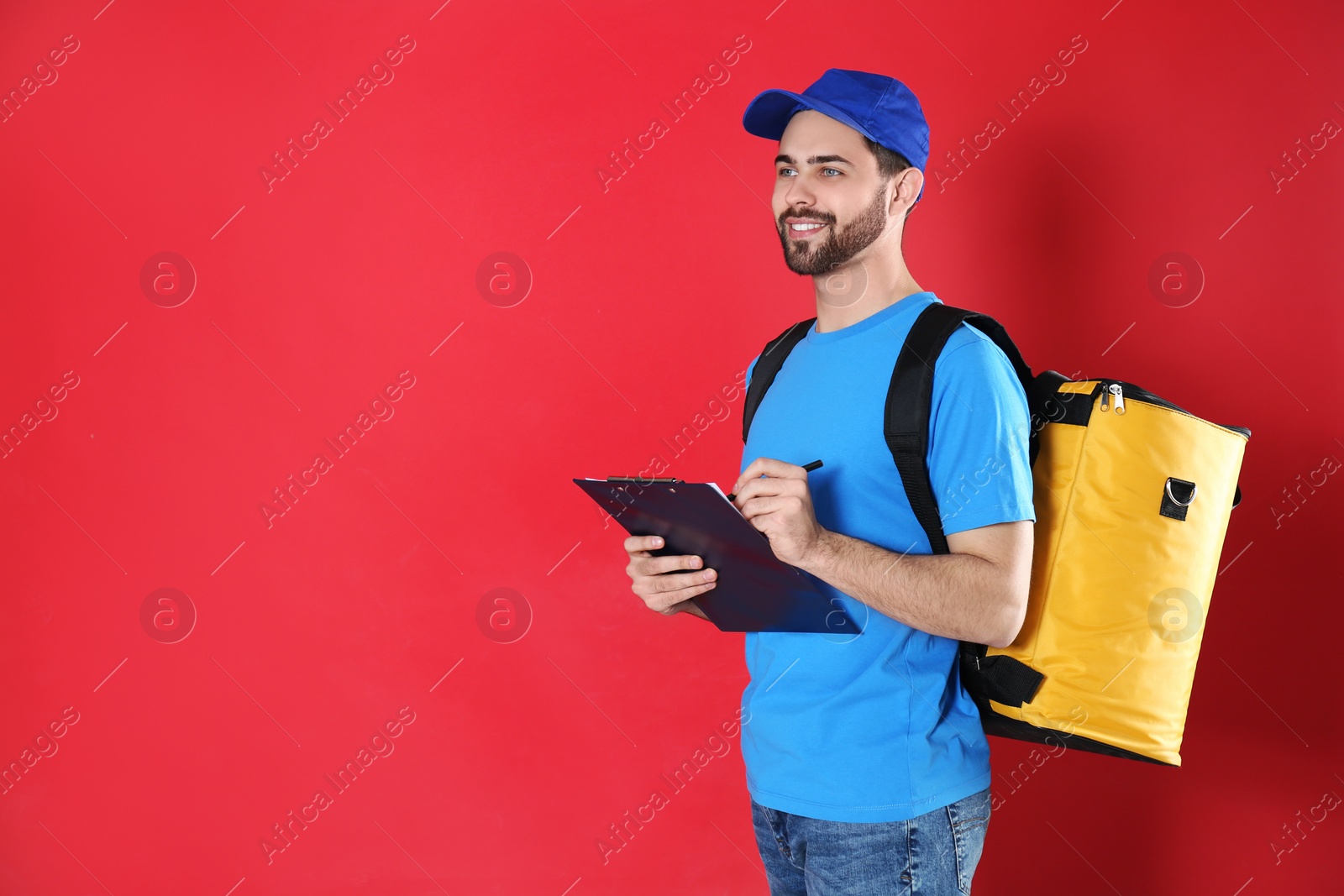 Photo of Courier with thermo bag and clipboard on red background, space for text. Food delivery service