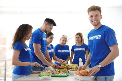 Team of volunteers near table with food indoors