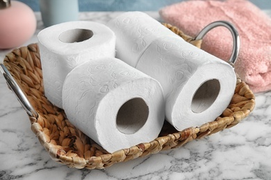 Photo of Wicker tray with toilet paper rolls on table